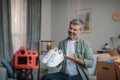 Cheerful elderly european man blogger with beard records video review on shoes, unpacks purchases Royalty Free Stock Photo