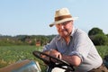 Cheerful, elderly gardener on his tractor