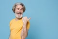 Cheerful elderly gray-haired mustache bearded man in casual yellow t-shirt posing isolated on blue wall background