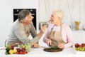Cheerful Elderly Husband Feeding Wife Tasting Dinner Cooking In Kitchen Royalty Free Stock Photo
