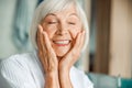 Cheerful elderly lady touching her face and closing eyes Royalty Free Stock Photo