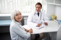 Cheerful elderly lady visiting practitioner and smiling