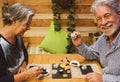 Cheerful elderly man with white hair and beard enjoying japanese food with his wife. Outdoors on a wooden table with sushi on the