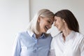 Cheerful elderly mother touch foreheads adult daughter laughing enjoy moment
