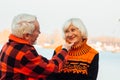 Cheerful elderly people a woman and a man are sitting on the stones and hugging on the lake, against the background of the bridge Royalty Free Stock Photo