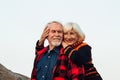 Cheerful elderly people a woman and a man are sitting on the stones and hugging on the lake, against the background of the bridge Royalty Free Stock Photo