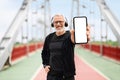 Cheerful elderly sportsman showing phone with white blank screen