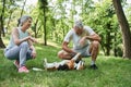 Cheerful elderly twosome locating at the grass on lawn or park