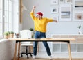 Cheerful elderly woman freelancer creative designer in a red hat having fun and dancing in workplace Royalty Free Stock Photo