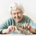 Cheerful elderly 96 years old woman sitting at table at home happy with her pension savings in her wallet after paying Royalty Free Stock Photo