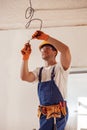 Cheerful electrician repairing electric cable on ceiling Royalty Free Stock Photo