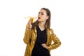 Cheerful elegant woman in golden jacket eats banana