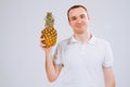 Cheerful and emotional guy holding a pineapple in his hand on a white background Royalty Free Stock Photo