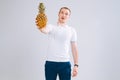 Cheerful and emotional guy holding a pineapple in his hand on a white background Royalty Free Stock Photo