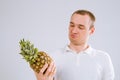 Cheerful and emotional guy holding a pineapple in his hand on a white background Royalty Free Stock Photo