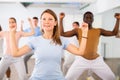 Happy flexible multiethnic men and women exercising active moves with group of people in dance center