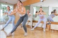 Group of happy young mature sportive women exercising dancing moves with instructor in modern gym studio Royalty Free Stock Photo