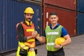 Cheerful engineer and foreman shaking hands while checking cargo freight container in shipping yard