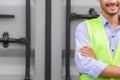 Cheerful engineer man in hard hat with arms crossed at cargo container