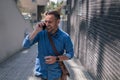 Cheerful entrepreneur talking on smart phone while walking by building in the city Royalty Free Stock Photo
