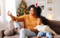 Cheerful ethnic family: happy mother taking selfie with child congratulating each other at Christmas in a cozy room at home Royalty Free Stock Photo