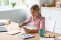 Cheerful european blonde teen girl pupil learning remote by phone using app, watching online lesson Royalty Free Stock Photo