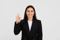 Cheerful european businesswoman giving an OK hand gesture to signify approval or success