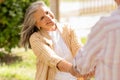 Cheerful european mature gray haired woman hold man hand, enjoy date together in park, have fun
