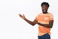 Cheerful and excited african-american man with beard and afro hairstyle introduce something interesting, pointing hands Royalty Free Stock Photo