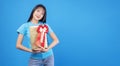 Cheerful excited asian woman holding gold gift box with red ribbon for amazed festive over isolated blue background. Surprise Royalty Free Stock Photo