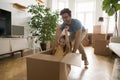 Cheerful excited dad pushing forward cardboard box with little daughter