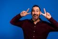 Cheerful excited Latin businessman showing victory sign and looking at camera. Happy handsome middle aged manager Royalty Free Stock Photo