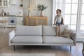 Cheerful excited little kid jumping on couch at home