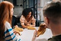 Cheerful excited multiethnic friends playing gambling board game sitting at table in room with modern interior. Diverse Royalty Free Stock Photo