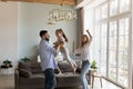 Cheerful excited parents and little daughter kid dancing to music