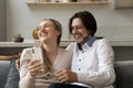 Cheerful excited 40s couple using mobile phone at home