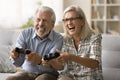 Cheerful excited senior couple playing online video game