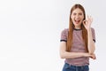 Cheerful, excited woman in striped t-shirt have no worried, feeling confident and relaxed, show okay, agree sign wink