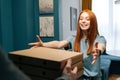 Cheerful excited young woman receiving paper boxes with pizza from unrecognizable courier male on doorway at home. Royalty Free Stock Photo