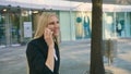 Cheerful executive girl waving with hand. Adult blond businesswoman in suit sitting on bench and waving with hand