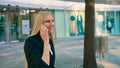 Cheerful executive girl waving with hand. Adult blond businesswoman in suit sitting on bench and waving with hand