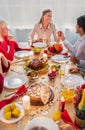 Happy extended family sitting at served table with holiday meal, having festive Thanksgiving or Christmas dinner at home