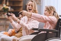 cheerful family with disabled child in wheelchair playing with joysticks together