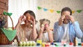 Cheerful family having fun preparing for Easter and putting colored eggs to eyes Royalty Free Stock Photo