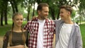 Cheerful family hugging and smiling into camera at park, trustful relationship