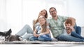 Cheerful family sitting on the carpet in the new living room Royalty Free Stock Photo