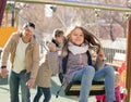 Cheerful family spending time at children swings Royalty Free Stock Photo