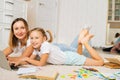 Cheerful family using laptop computer together lying on floor in children room with modern light interior, looking at Royalty Free Stock Photo