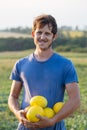 Cheerful farmer holding fresh melon crop on the field at organic eco farm.