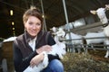 Cheerful farmer woman with goats in barn